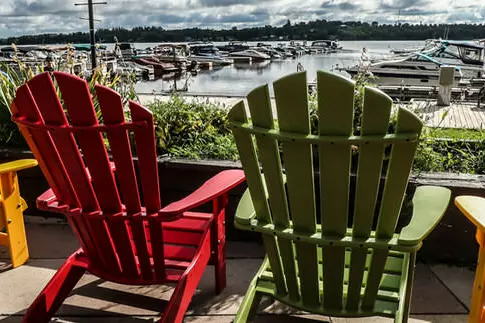 Six chaises longues Muskoka sont placées dans une rangée surplombant un port pittoresque